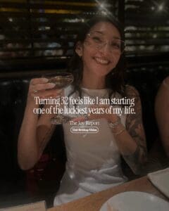 Text reads "Turning 32 feels like I am starting one of the luckiest years of my life." over a photo of a girl holding an espresso martini and smiling wearing white