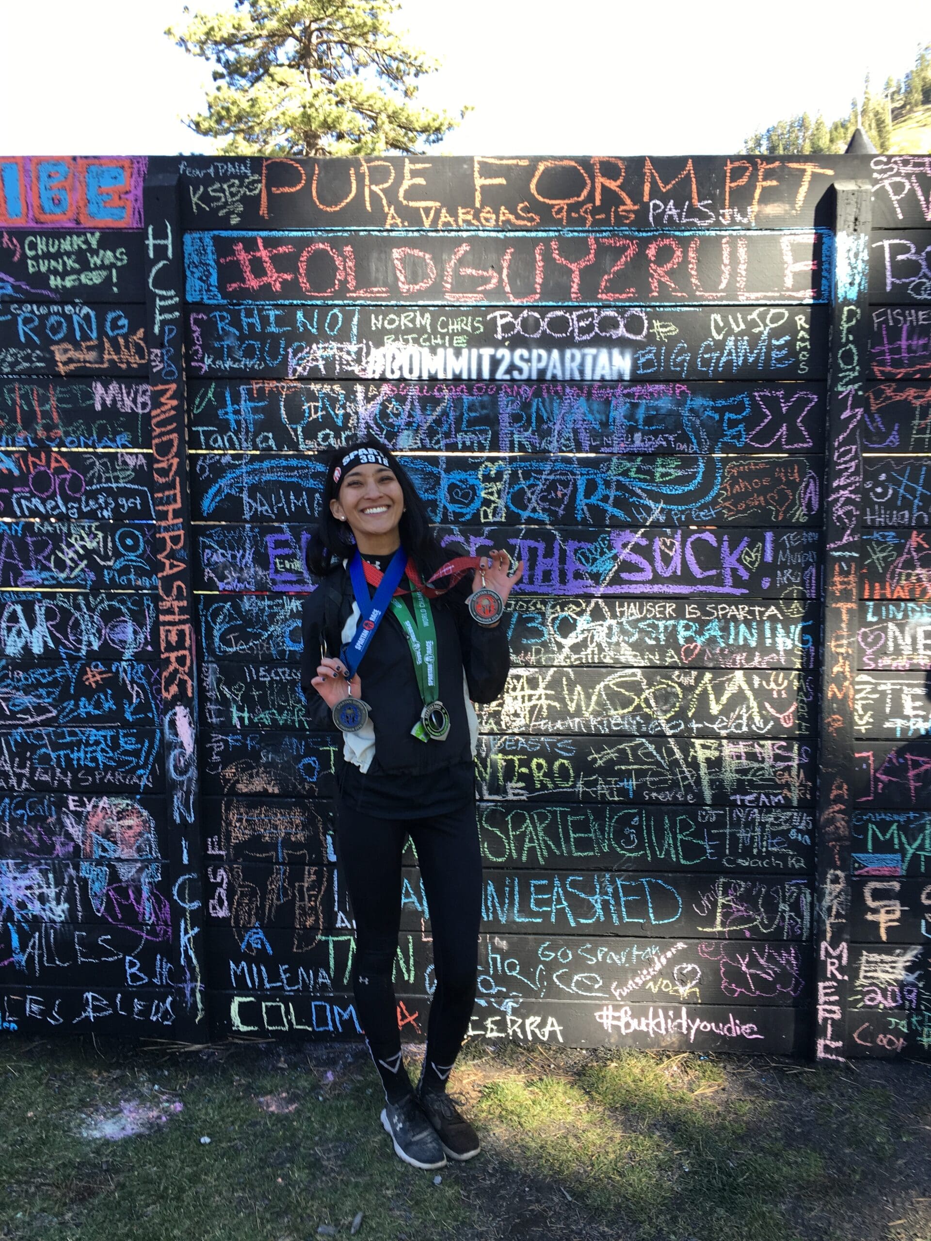 2016 Spartan Trifecta finisher Taylor Nakakihara in front of a signed wall of other participants at the 2016 Spartan World Championships in Olympic Valley, Lake Tahoe, California