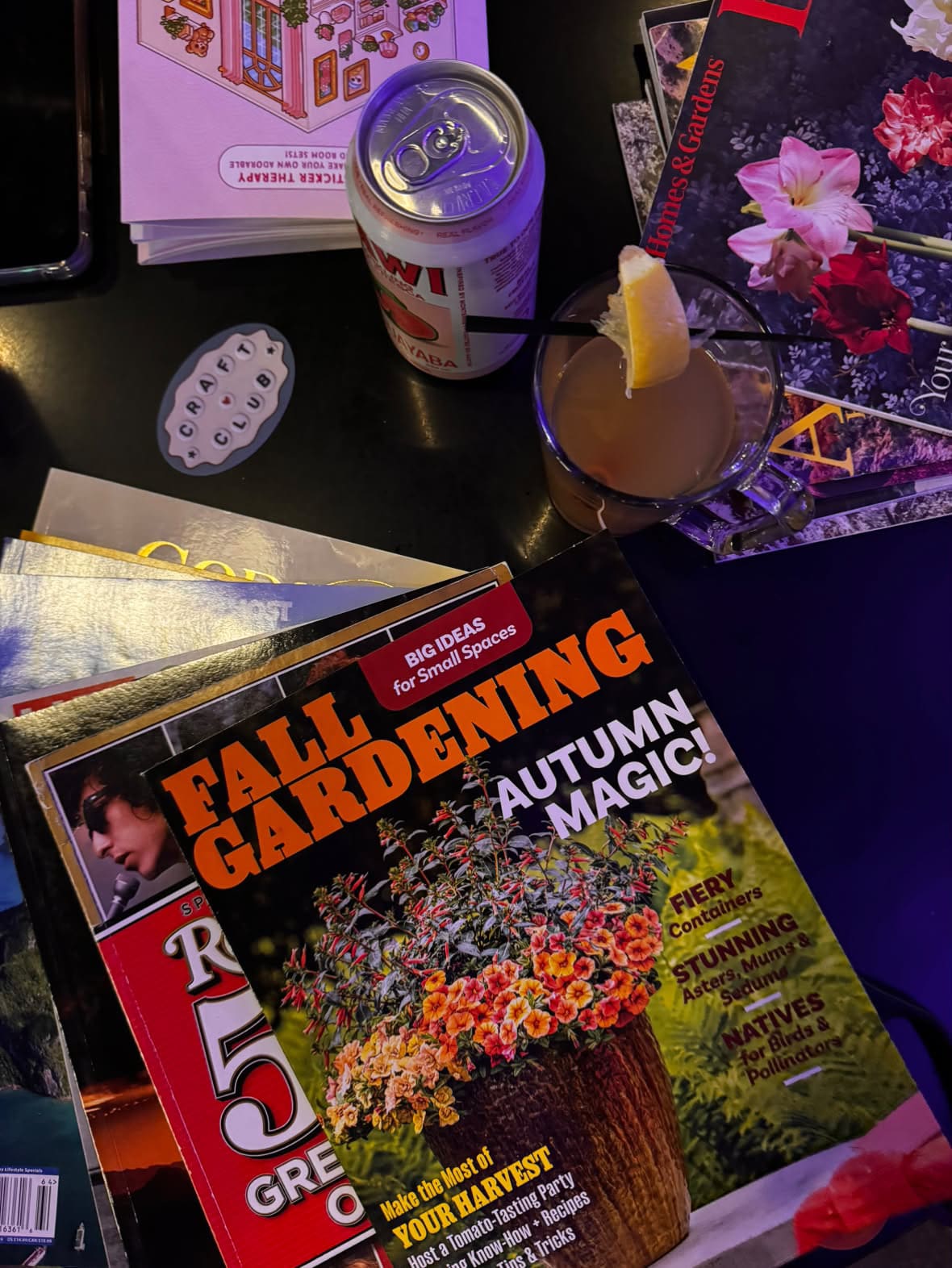 Stack of magazines, a can of beer, a hot toddy and a Craft Club sticker on a table